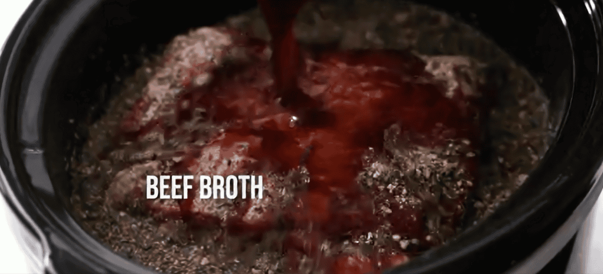 Beef broth being poured over the roast in a crockpot. 