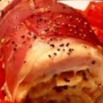 a dish with ham and tomatoes on a plate.