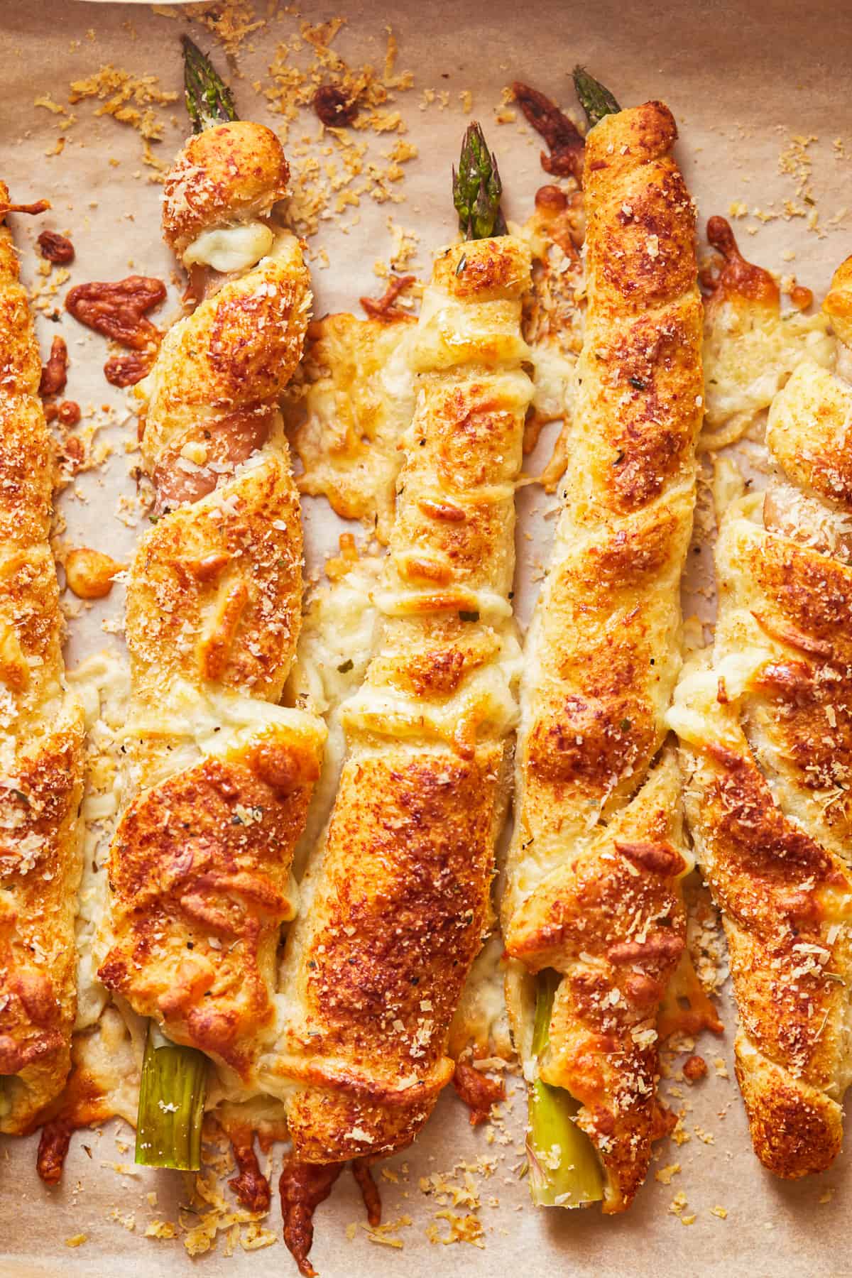 overhead view of asparagus crescent rolls pointing north-south on parchment paper.