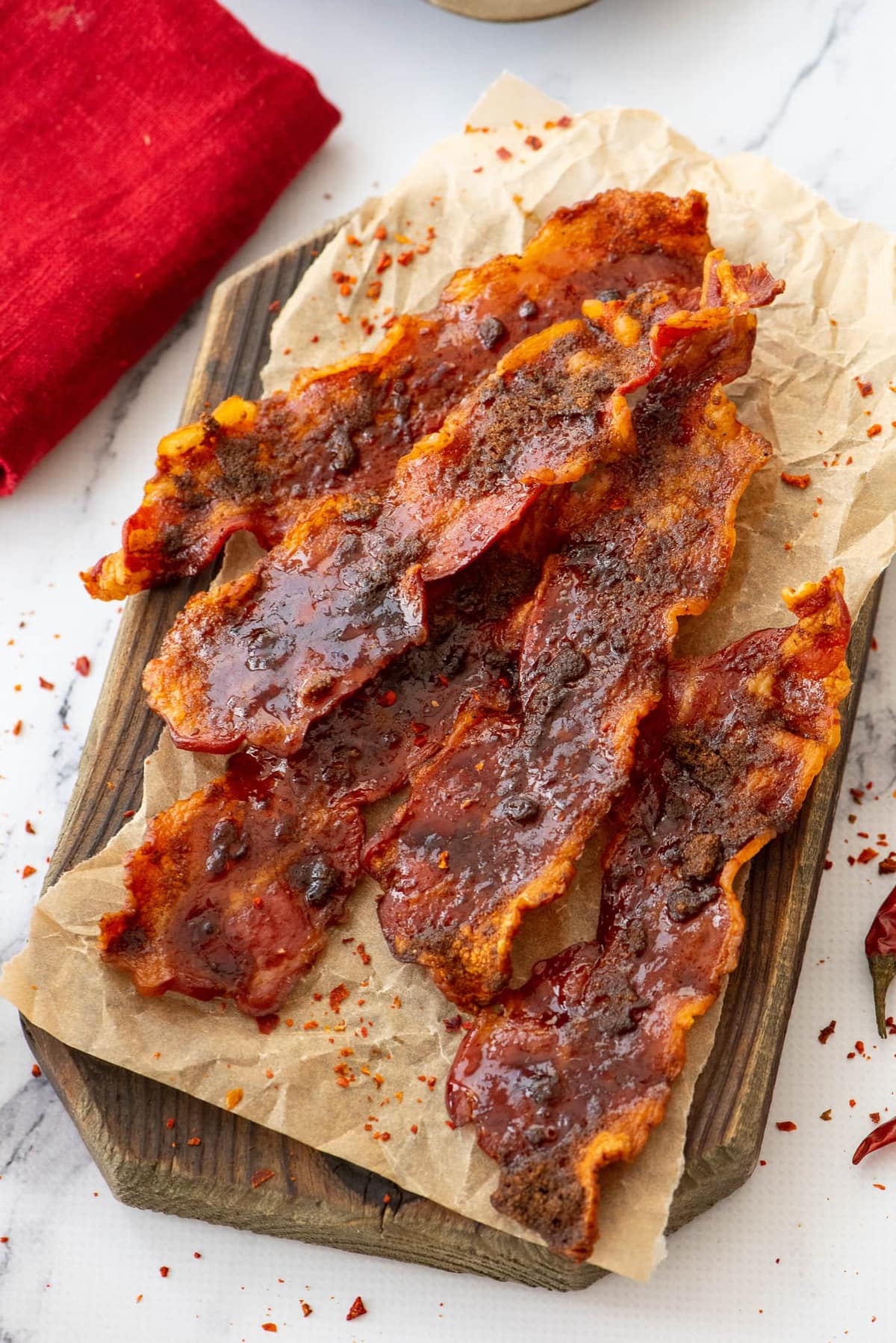 Spicy Brown Sugar Bacon will add a delicious sweet and spicy twist to your breakfast! This oven baked bacon recipe is so easy and so tasty. The cayenne pepper and brown sugar creates the perfect flavor, but you can leave that out if you want and just start baking bacon in the oven for the best bacon ever! strips of bacon on a wood board