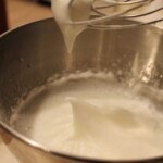 whipped cream being whisked into a bowl.
