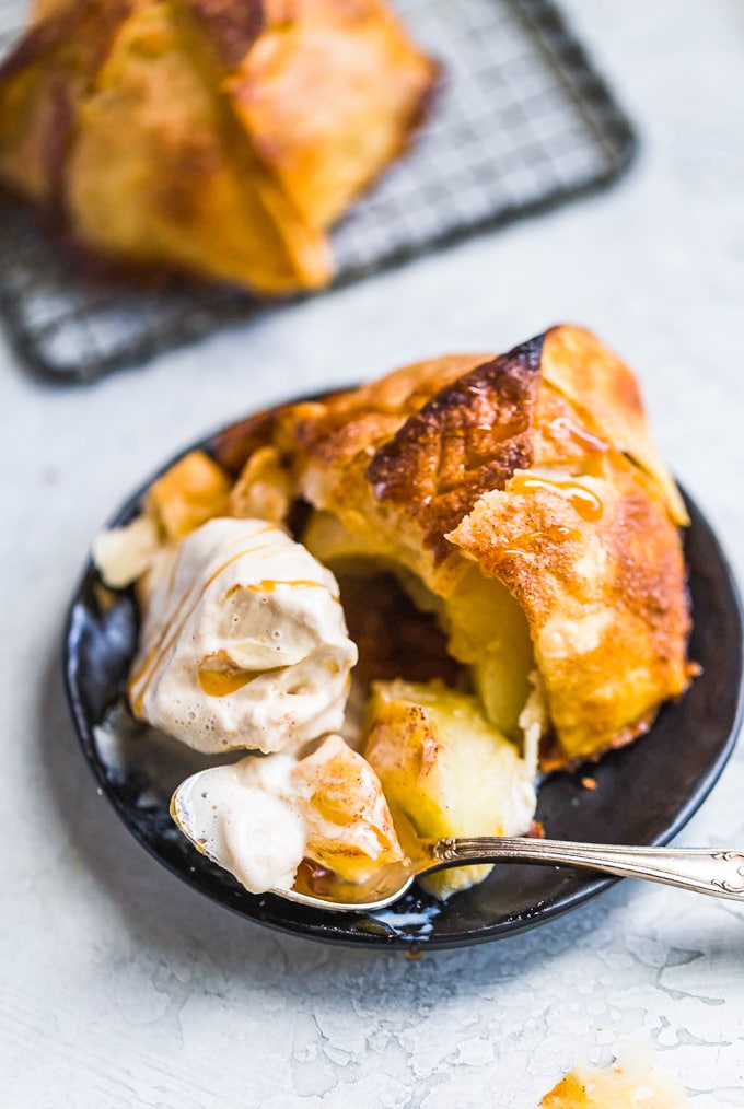 a partially eaten apple dumpling on a plate with ice cream.