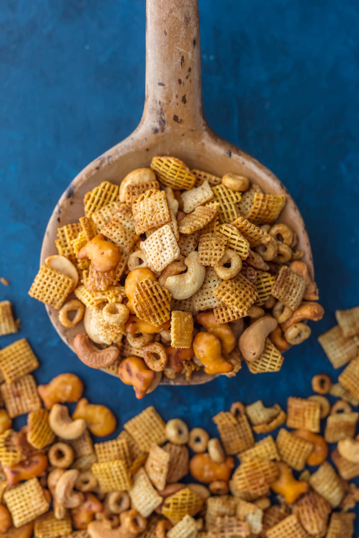 Overhead view of a scoop of party mix on a large wooden spoon.