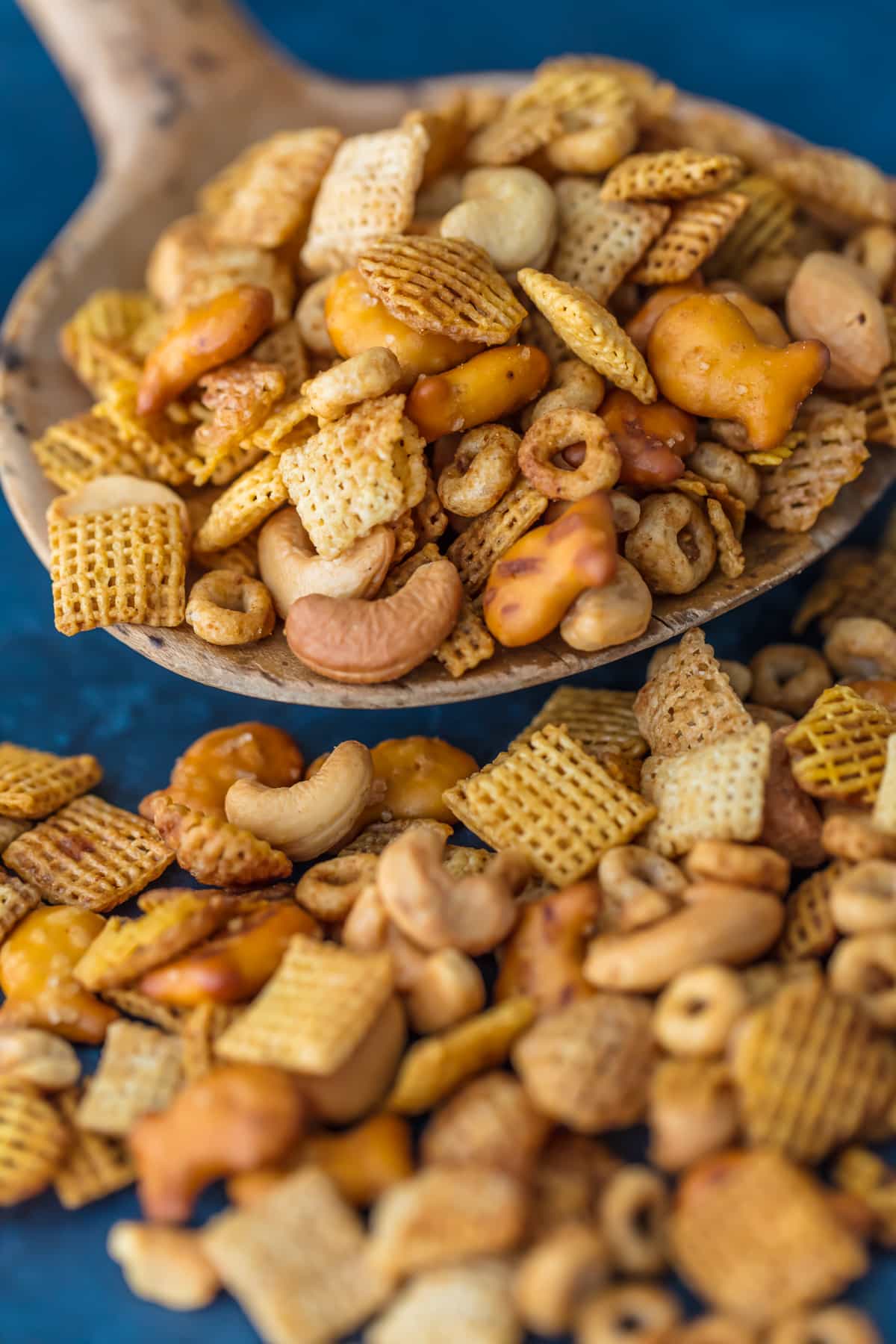 A large wooden spoon holding a scoop of chex mix.