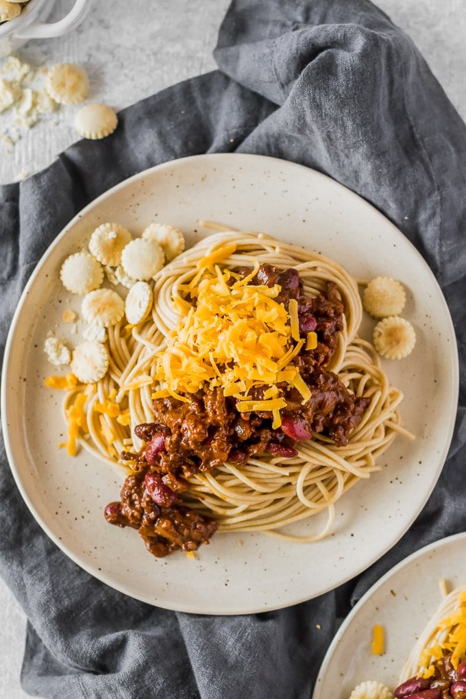 plate of spaghetti topped with chili, cheese, and crackers