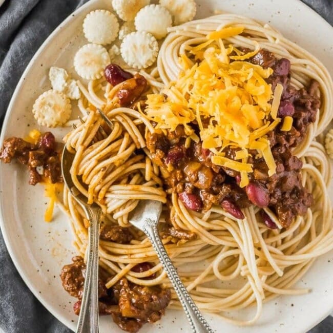 Cincinnati Chili is a delicious and unique Chili recipe atop spaghetti noodles and loaded with oyster crackers, cheese, beans, on onions. This Cincinnati Chili Recipe is both savory and sweet in all the right ways. This Cincinnati Style Chili is a must make for any Chili lover! 