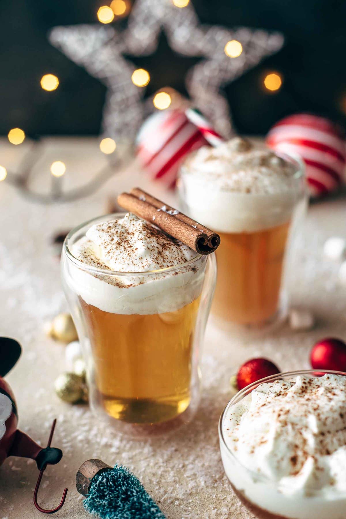 Caramel Apple Hot Toddy Cocktail topped with whipped cream and cinnamon sticks