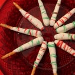 fanned out pretzel rods dipped in white chocolate with red and green chocolate drizzled across sitting on a plate