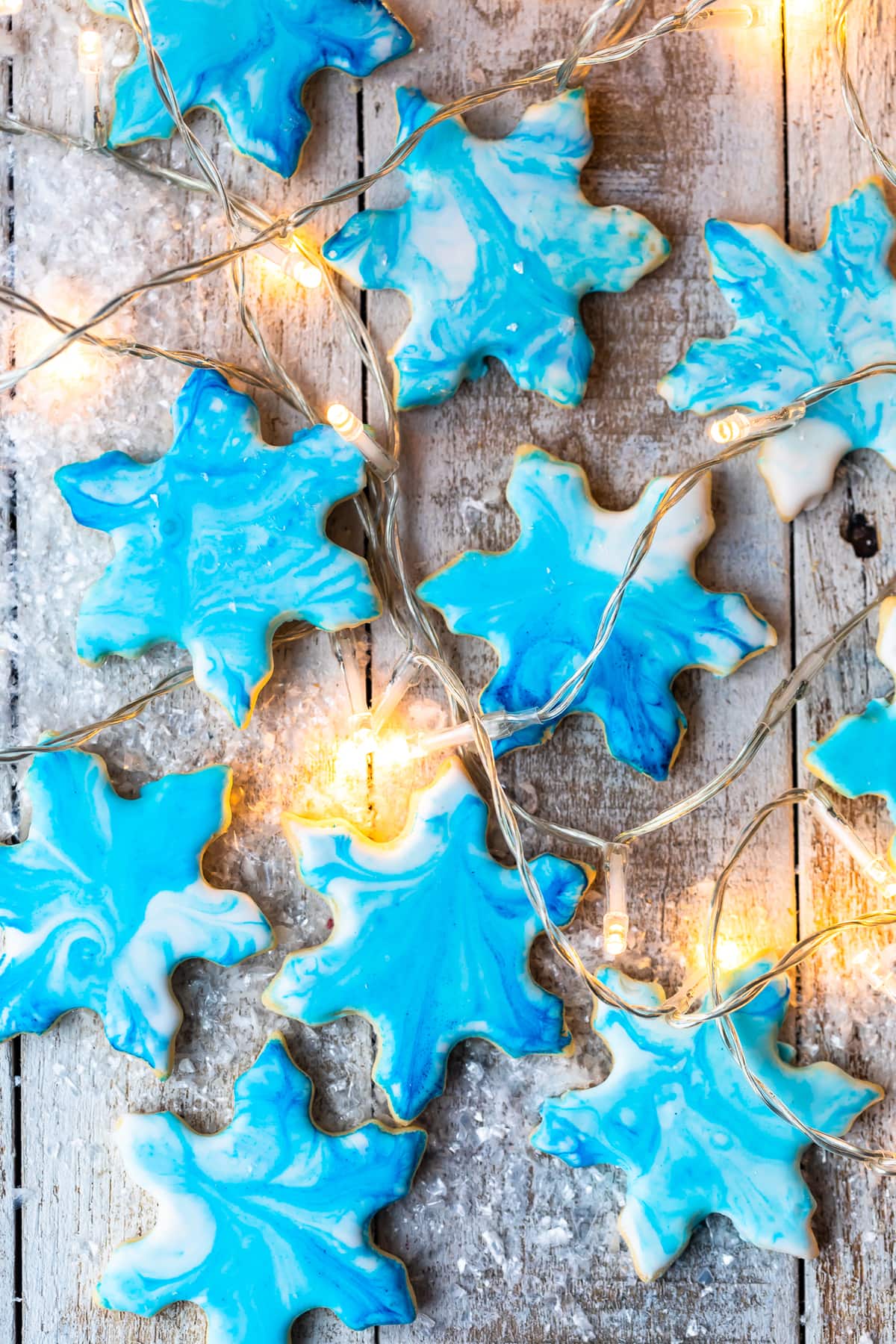 overhead view of blue snowflakes cookies intermixed with christmas lights