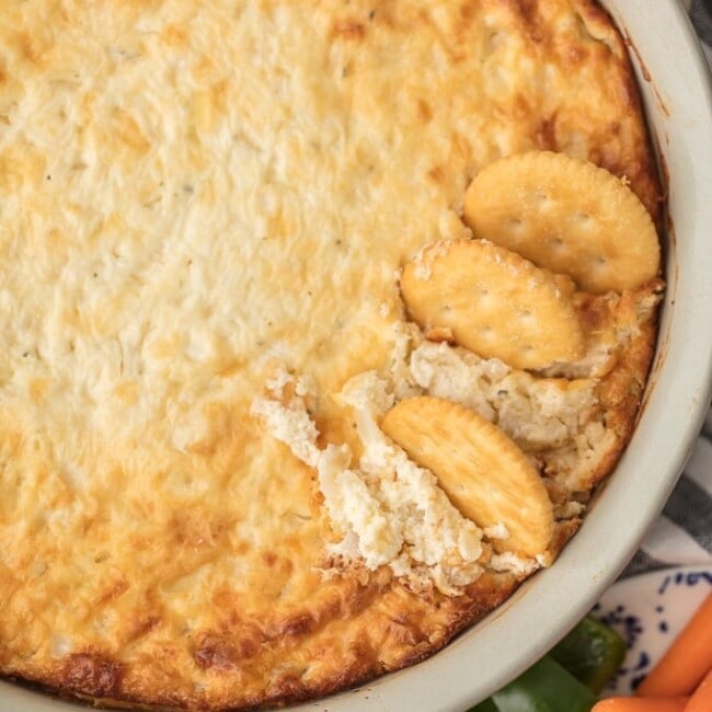 crackers in hot onion dip in a white baking dish