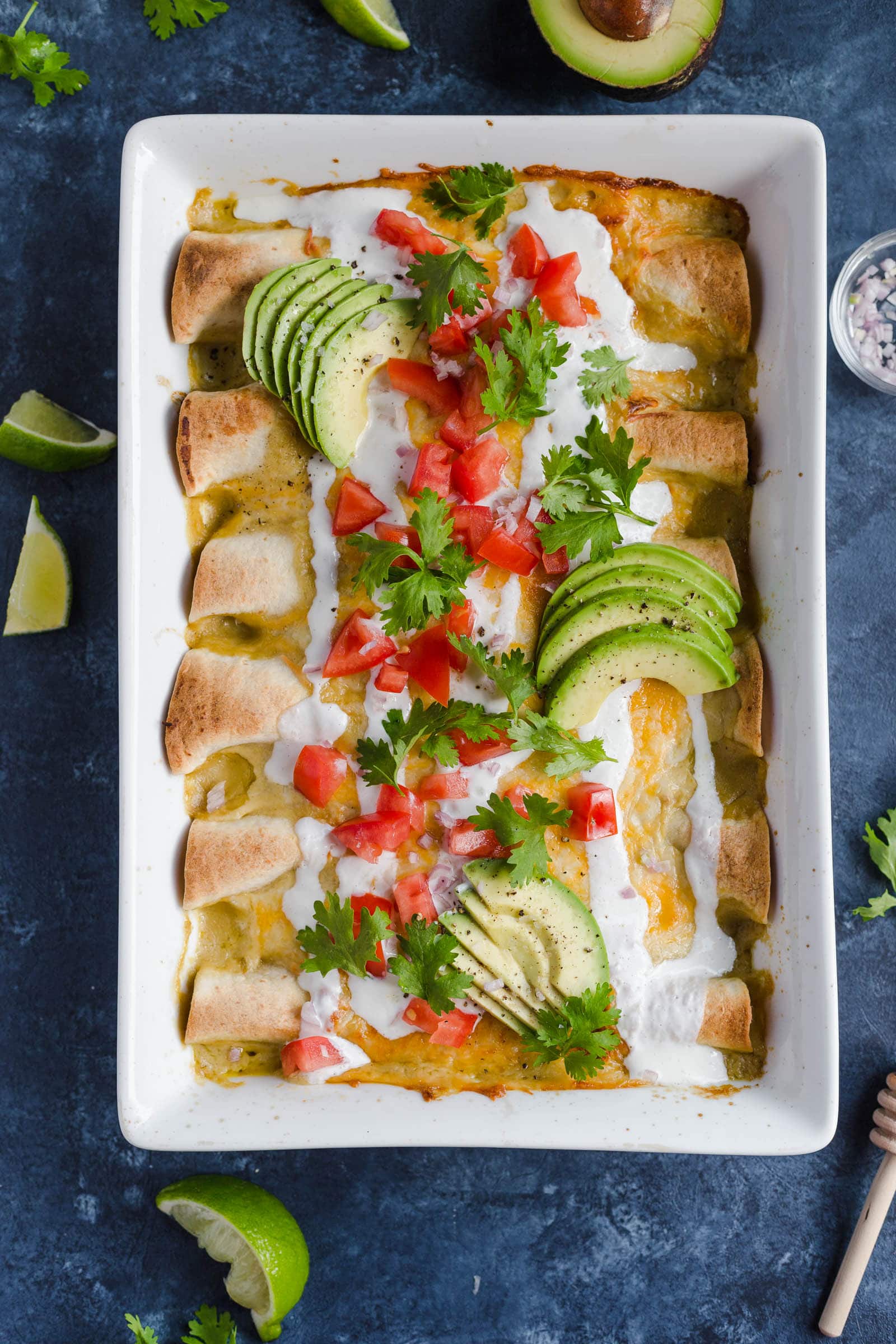 A baking dish full of easy chicken enchiladas made with cheese, sour cream, enchilada sauce, and more