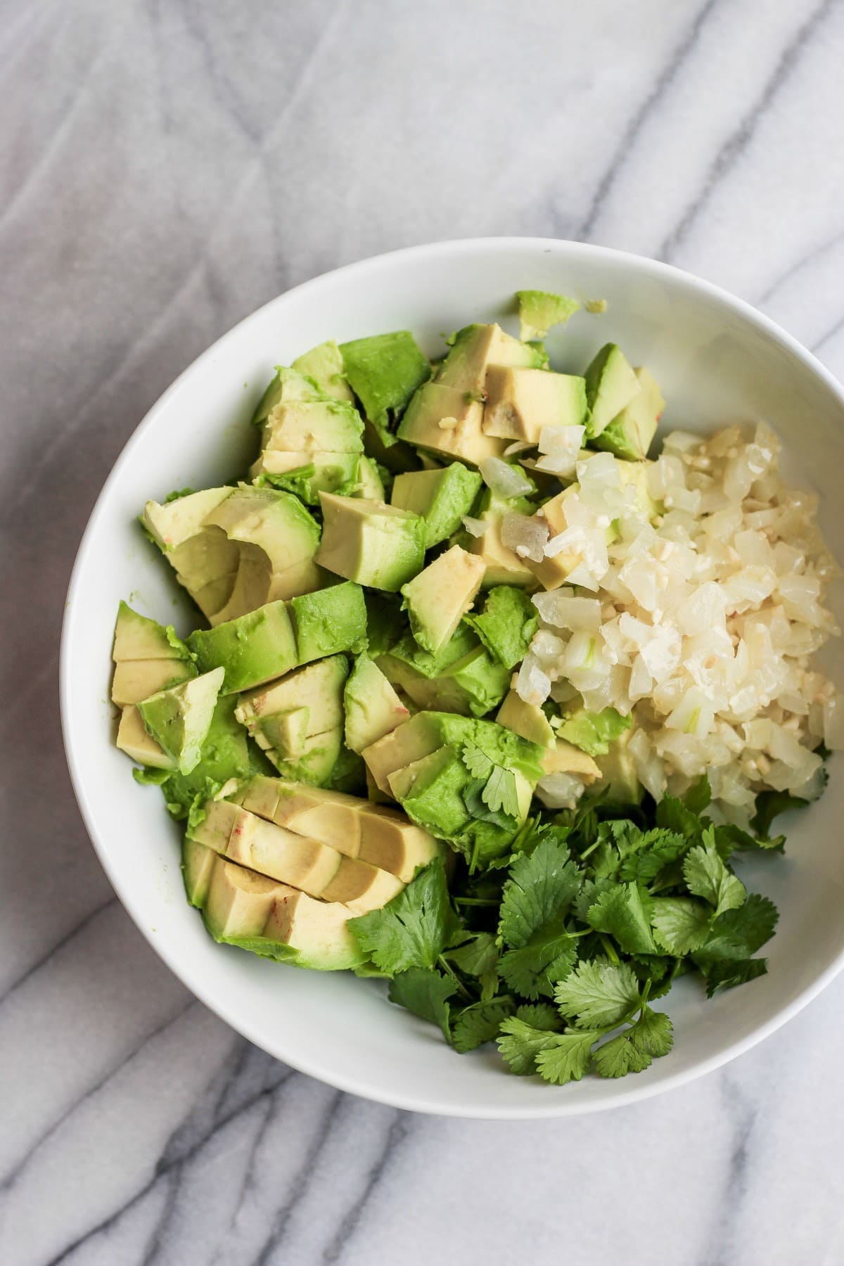 a bowl filled with chopped avocado, onions, and cilantro