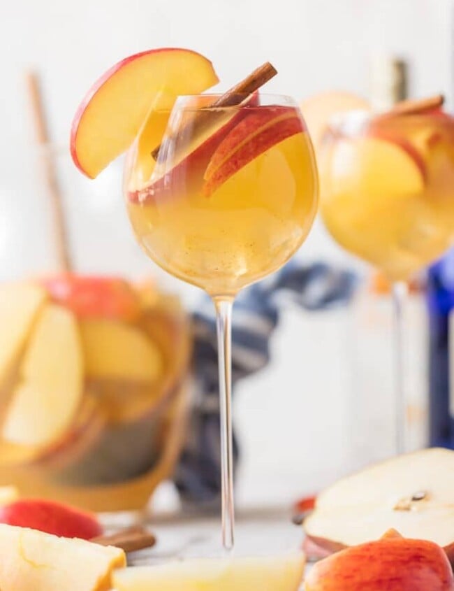 Apple Pie Sangria is a light, refreshing, delicious, and EASY Caramel Apple Sangria! This Fall Sangria Recipe is the hit of every party I take it to! Apple Pie Sangria is loaded with Apple Cider, Caramel Vodka, White Wine, Ginger Ale, and more! We call this Thanksgiving Sangria because it's Autumn in a glass. We have sangria recipes for every occasion, but this one is our favorite.