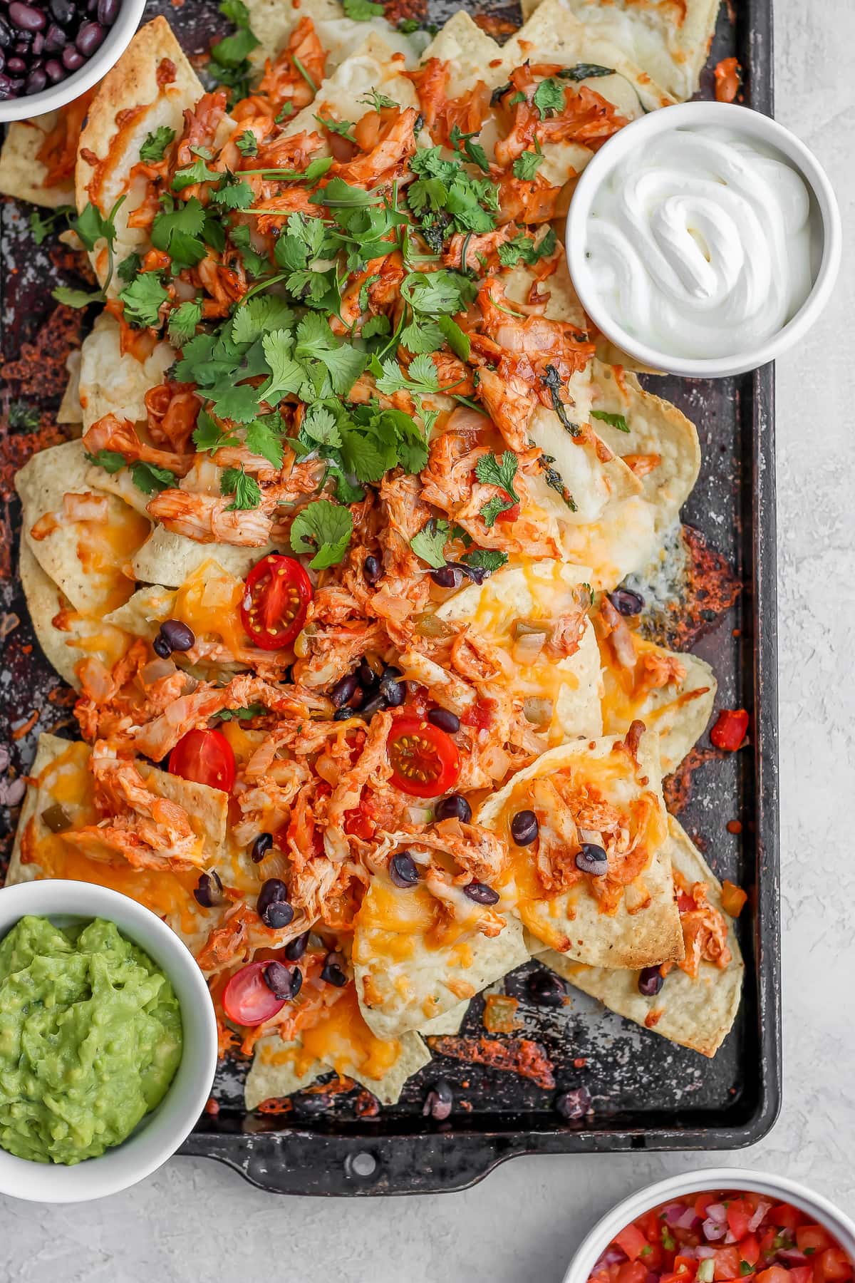 nachos topped with chicken, beans, cilantro, and more