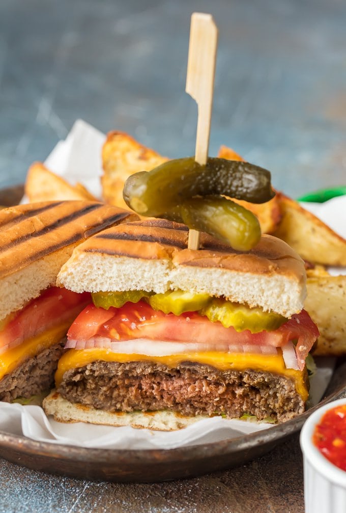 Stovetop Burgers are easier than you might think! Once we learned How to Cook Burgers on the Stove it's our go-to easy dinner for anytime of year. Cooking Burgers on the Stove is a great way to make sure you cook a JUICY and PERFECT Stovetop Burger each and every time. Hamburgers on the Stove is the only way to cook cheeseburgers! sliced stovetop cheese burger topped with lettuce tomato onion and pickle