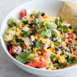 Mexican Dip is the perfect game day appetizer! This Mexican Dip recipe is filled with black beans, corn, feta, avocado, salsa, and so much more. It's crispy, fresh, and full of flavor! This Fresh Fiesta Dip will be a hit at any gathering. You could even turn this into a healthy fiesta salad!