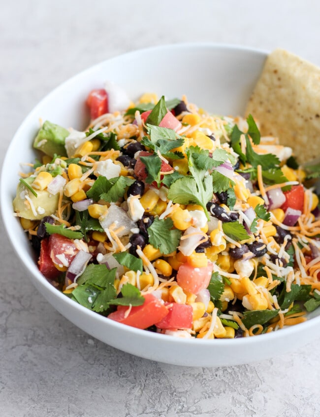 Mexican Dip is the perfect game day appetizer! This Mexican Dip recipe is filled with black beans, corn, feta, avocado, salsa, and so much more. It's crispy, fresh, and full of flavor! This Fresh Fiesta Dip will be a hit at any gathering. You could even turn this into a healthy fiesta salad!