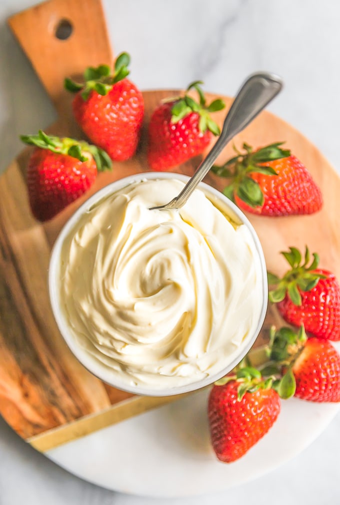 Image of homemade Mascarpone Cheese, in a bowl, surrounded by strawberries. 
