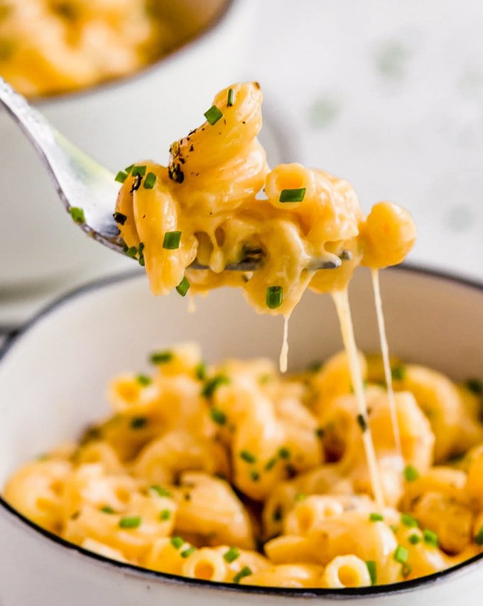 Mac and cheese on a fork, above a bowl of macaroni