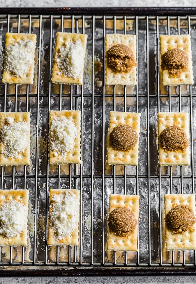 crackers lined up on a baking rack, topped with mounds of brown sugar and grated cheese