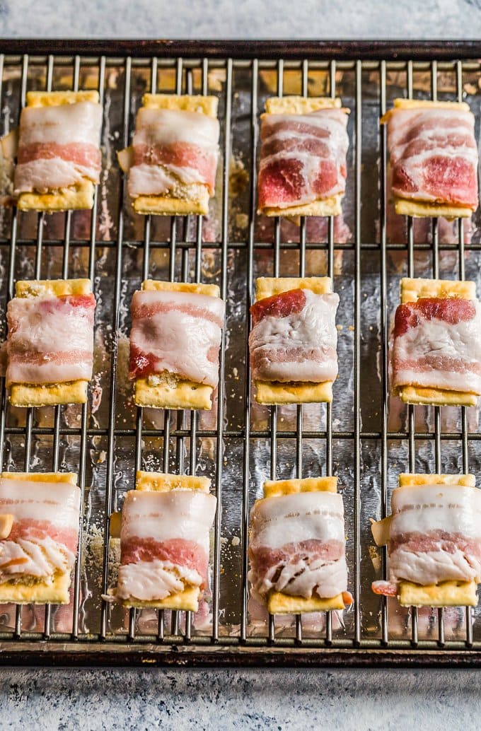 crackers lined up on a backing rack, wrapped in uncooked bacon