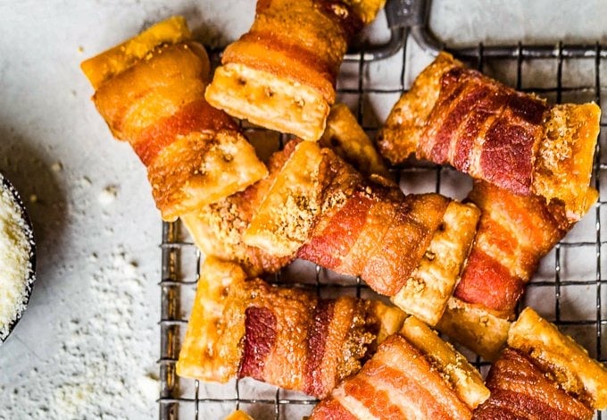 bacon wrapped crackers piled on to a cooling rack