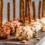 Mini Cheese Ball Bites are the perfect easy appetizer to serve at holiday parties. These tasty little cheese balls are made with dried fruit and cream cheese, rolled in bacon or nuts, and finished off with a pretzel stick. Make these Mini Cheese Ball Bites for a New Year's Eve appetizer or any simple gathering!