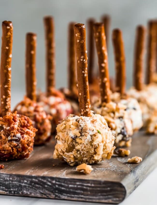 Mini Cheese Ball Bites are the perfect easy appetizer to serve at holiday parties. These tasty little cheese balls are made with dried fruit and cream cheese, rolled in bacon or nuts, and finished off with a pretzel stick. Make these Mini Cheese Ball Bites for a New Year's Eve appetizer or any simple gathering!