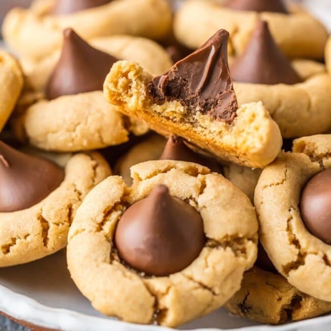 Peanut Butter Blossoms are a classic cookie recipe that is easy to make and loved by all! This BEST Peanut Butter Kiss Cookies Recipe has been in our family for years. Chocolate Peanut Butter Cookies are perfect for Christmas baking, but also made for enjoying year round, especially at Summer BBQs. When it comes to favorite cookie recipes, these Peanut Butter Hershey Kiss Cookies can't be beat. 