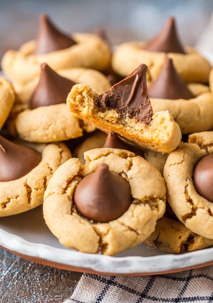 Peanut Butter Blossoms are a classic cookie recipe that is easy to make and loved by all! This BEST Peanut Butter Kiss Cookies Recipe has been in our family for years. Chocolate Peanut Butter Cookies are perfect for Christmas baking, but also made for enjoying year round, especially at Summer BBQs. When it comes to favorite cookie recipes, these Peanut Butter Hershey Kiss Cookies can't be beat. 