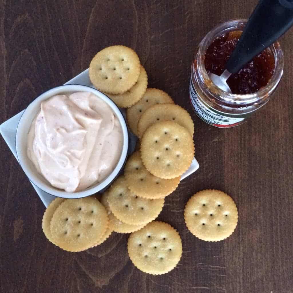 Pepper Jelly Cream Cheese Dip in a bowl, surrounded by crackers.