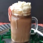 hot chocolate in a glass mug topped with whipped cream and a candy cane
