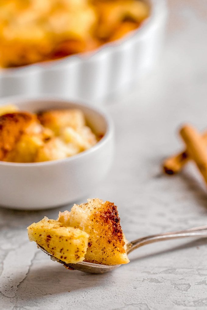 Pineapple Bread Pudding is a simple and delicious dish that is just perfect for Christmas. It works as both a side dish and a dessert, meaning you have plenty of reasons to eat it. The texture and flavor of this easy pineapple dessert is so good! It's fluffy, sweet, and the cinnamon on top is the perfect addition. A spoon with a piece of pineapple bread pudding on it.