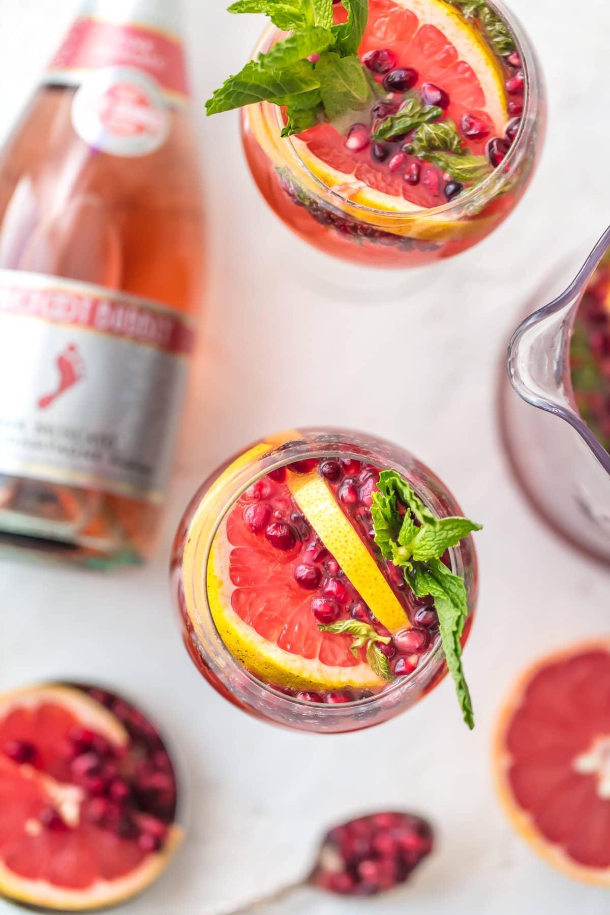 Glasses of champange sangria viewed from above, next to a bottle of pink moscato champagne