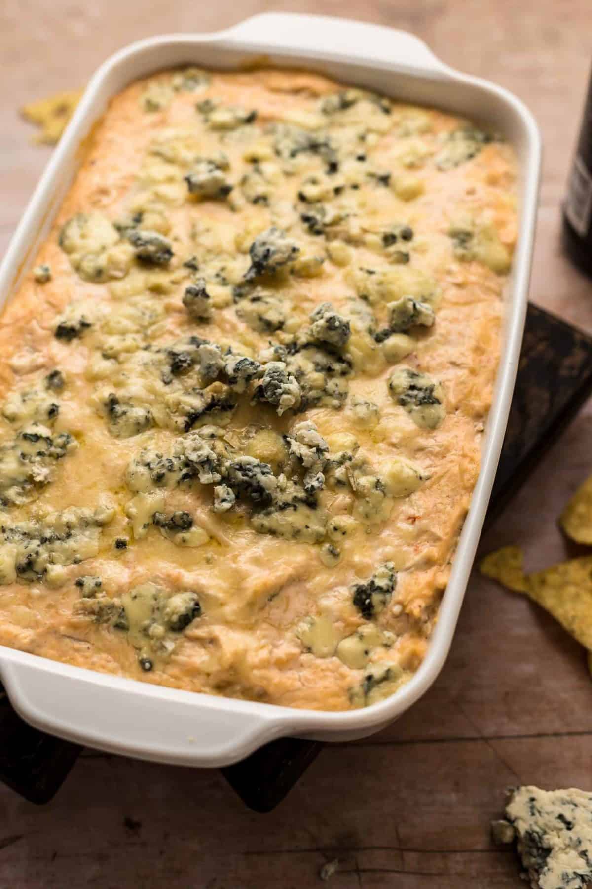 Beer Cheese Buffalo Chicken Dip is a fun and flavorful twist on a classic party recipe! This buffalo chicken dip with blue cheese and beer is just perfect for tailgating. Nothing goes better together than wings and beer (and cheese)! Baking dish filled with Beer Cheese Buffalo Chicken dip.