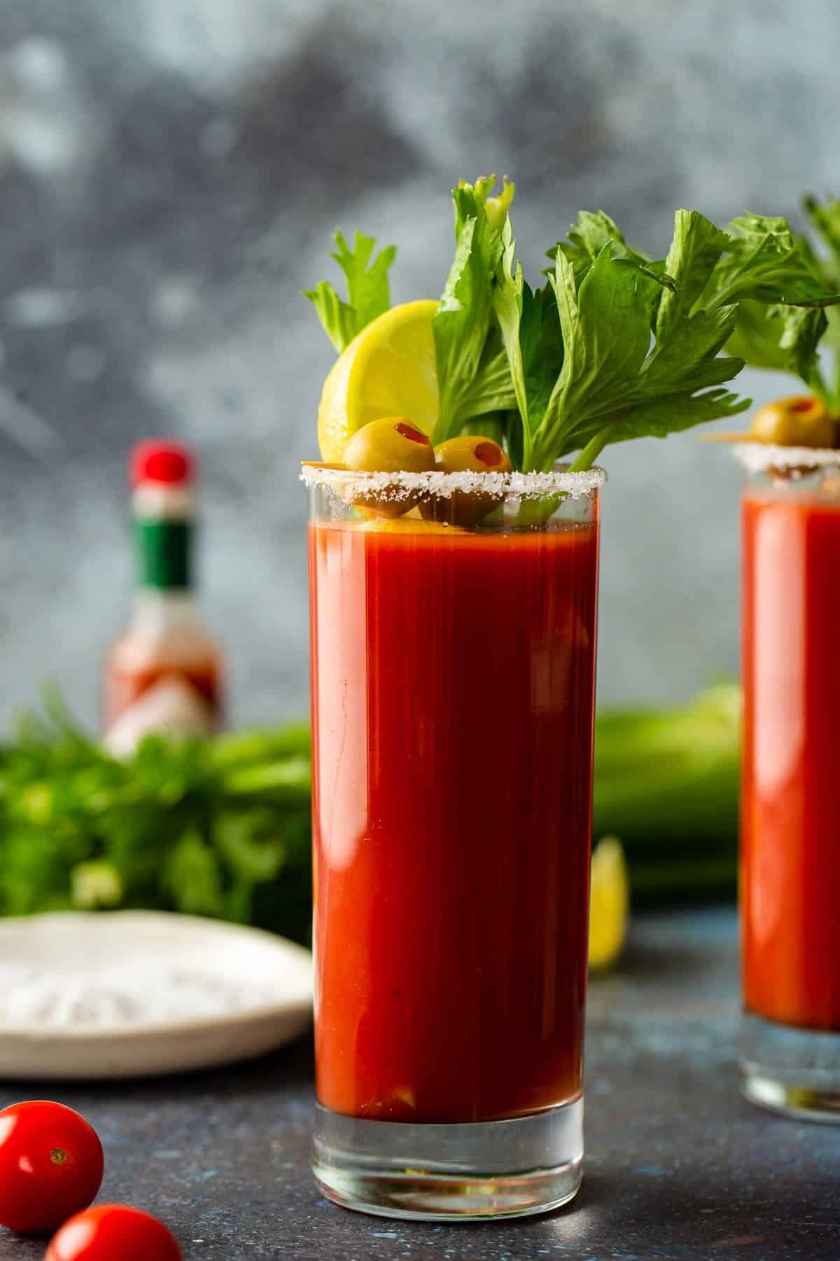 Bloody Mary cocktail with celery and hot sauce in the background