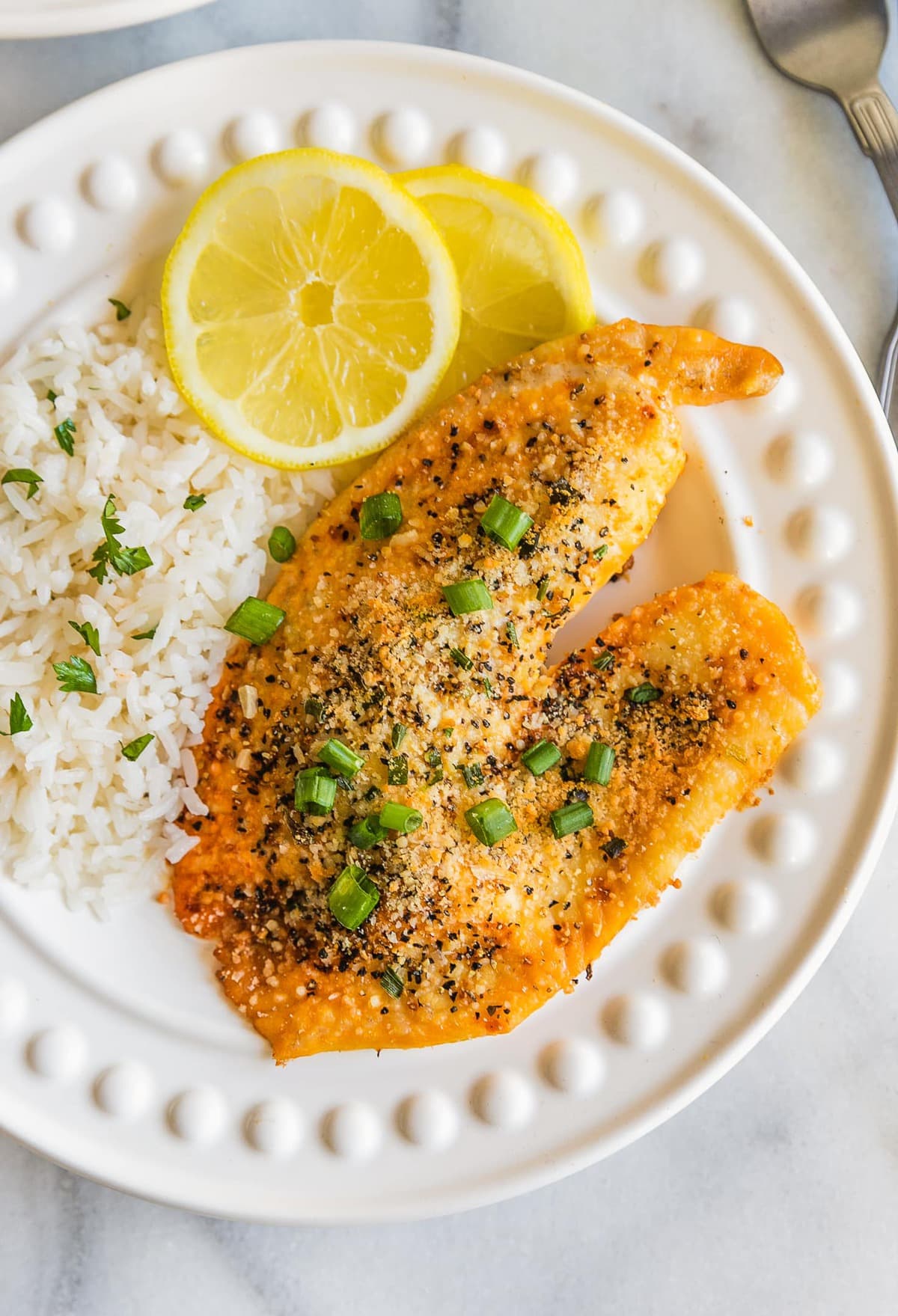 lemon pepper tilapia on a plate with rice