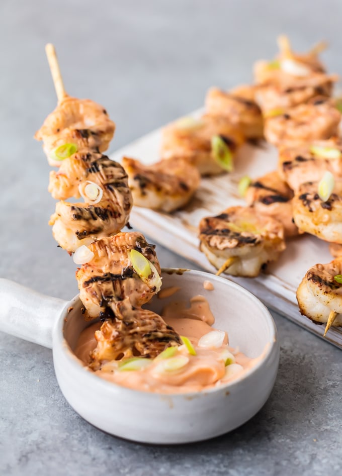 dipping a shrimp skewer into dipping sauce