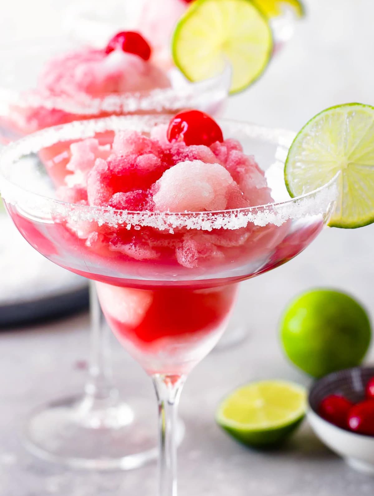 Frozen Margarita topped with cherries and garnished with lime.