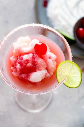 A frozen cherry limeade margarita garnished with a cherry.