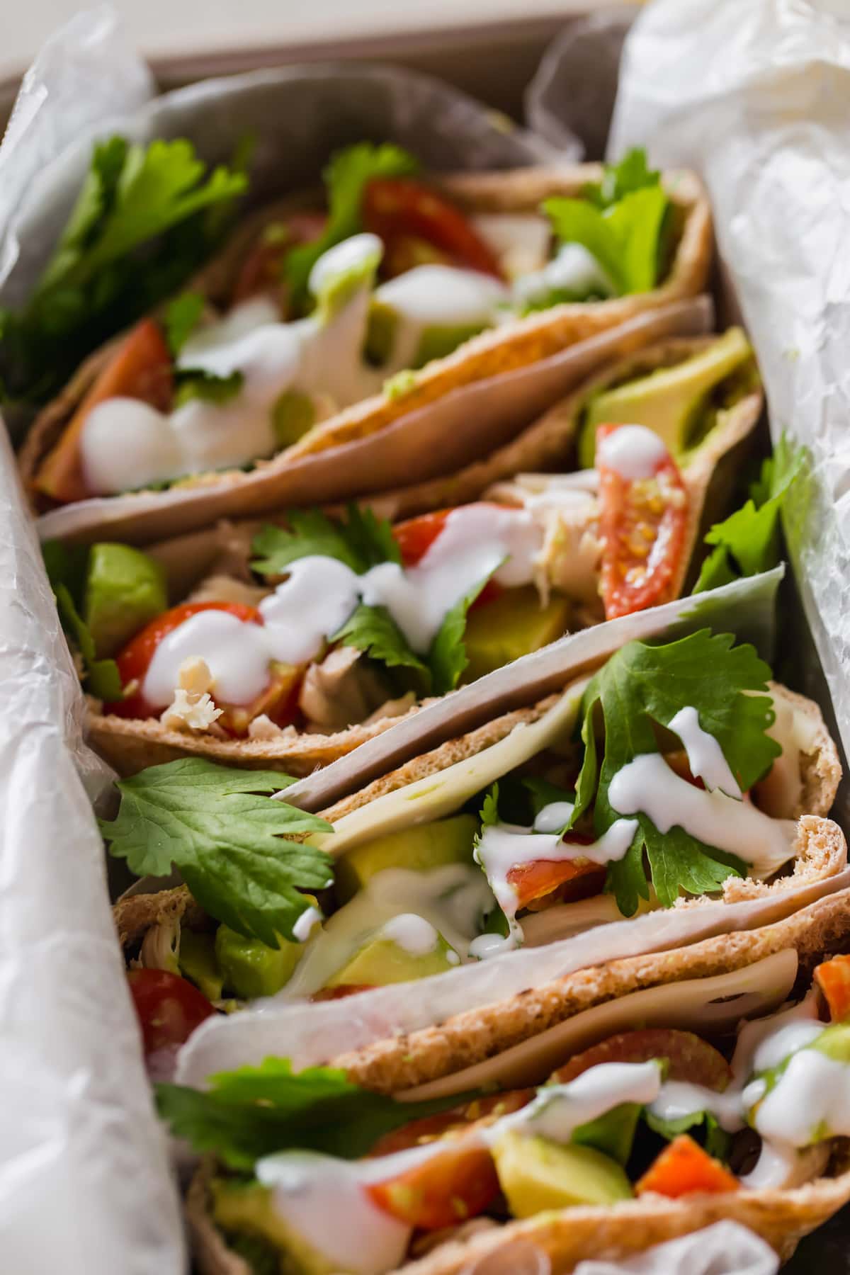 healthy chicken pitas lined up in a tray so that the filling is visible from an overhead view