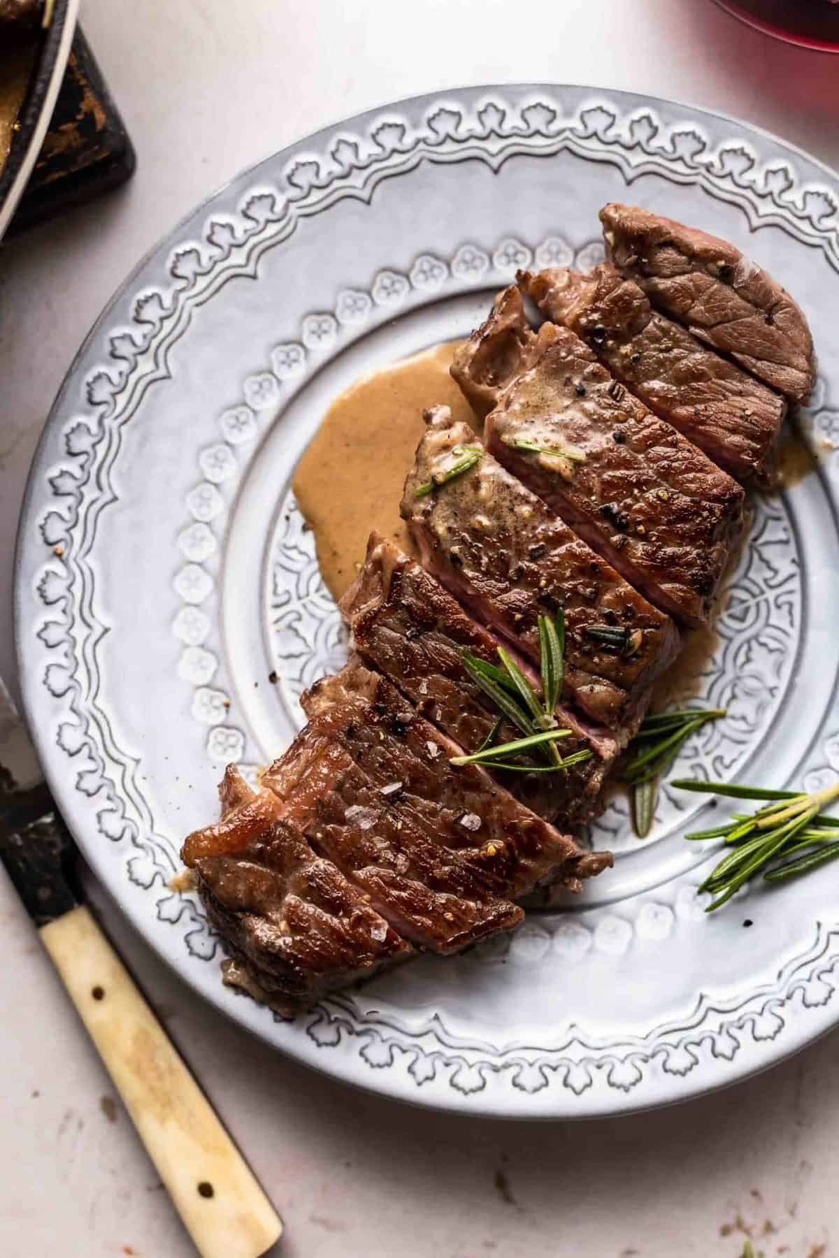 Plate of steak with rosemary and cream sauce.