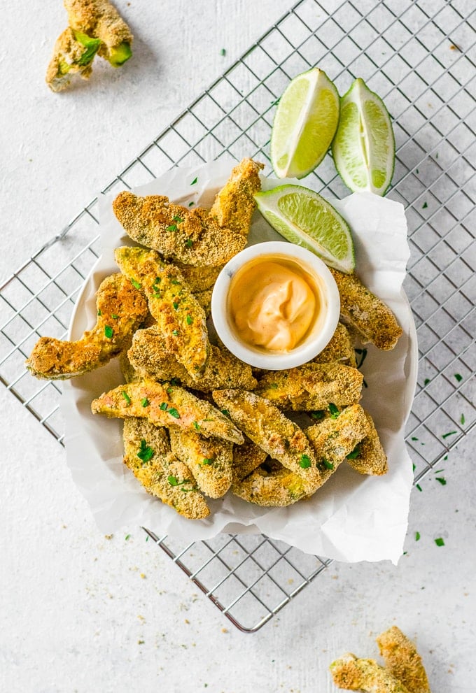 Avocado Fries in a bowl with lime wedges on a wire rack