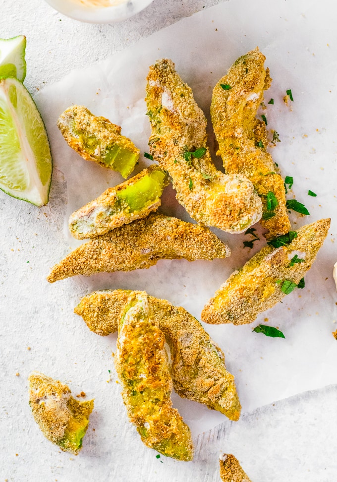 Avocado Fries next to a sliced lemon on a white countertop