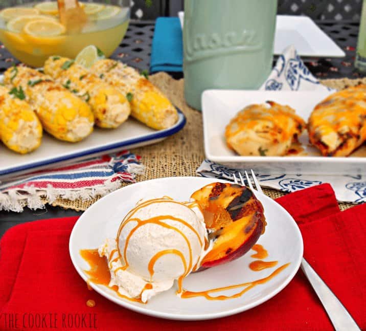 View of a table with grilled corn, chicken and peaches.