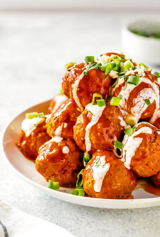 Buffalo Chicken Meatballs are one of our very favorite party appetizers. These Blue Cheese Stuffed Meatballs are relatively healthy, SO flavorful, and sure to please. If you're not sure what to serve for your next tailgating party, this Buffalo Chicken Meatballs Recipe is just the thing. Serve with Homemade Ranch! buffalo chicken meatballs drizzled with ranch on plate