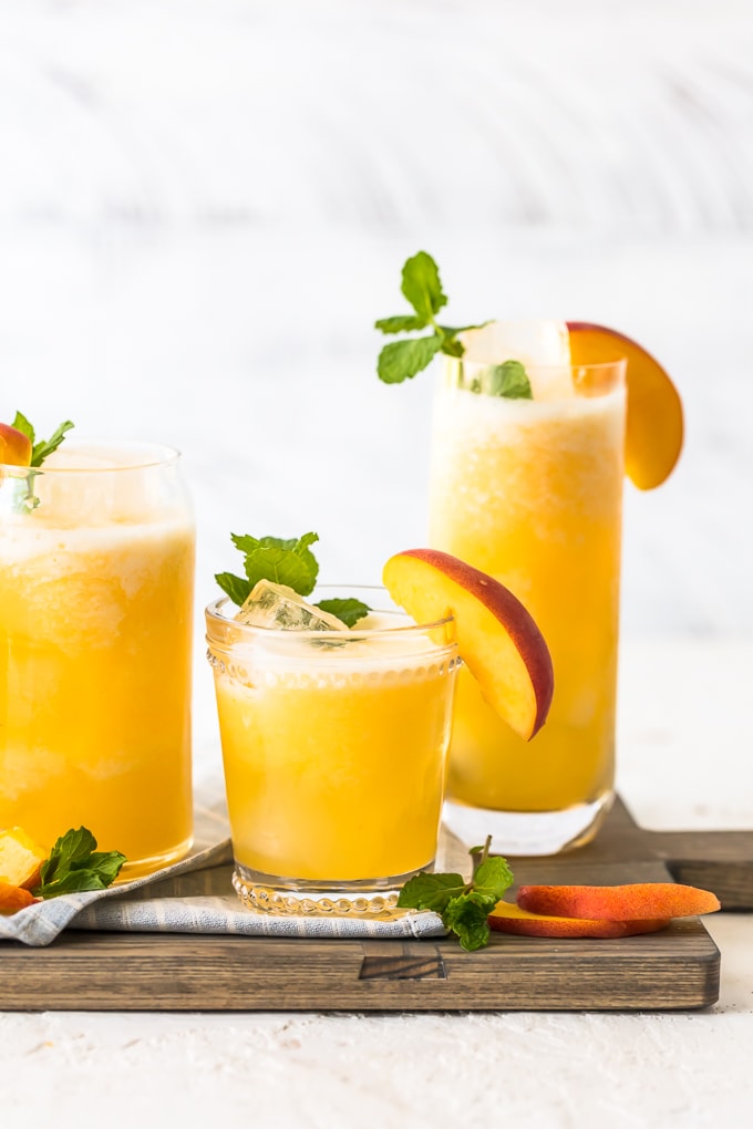 peach lemonade in glasses on wooden cutting board