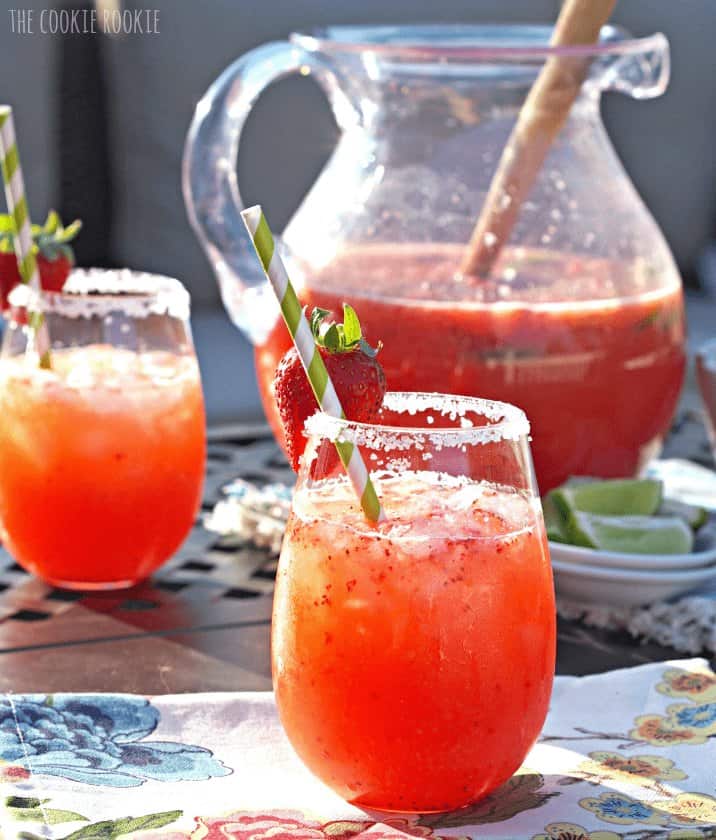 Strawberry Margarita Punch - The Cookie Rookie A pitcher of Margarita Punch and two glasses on a table.