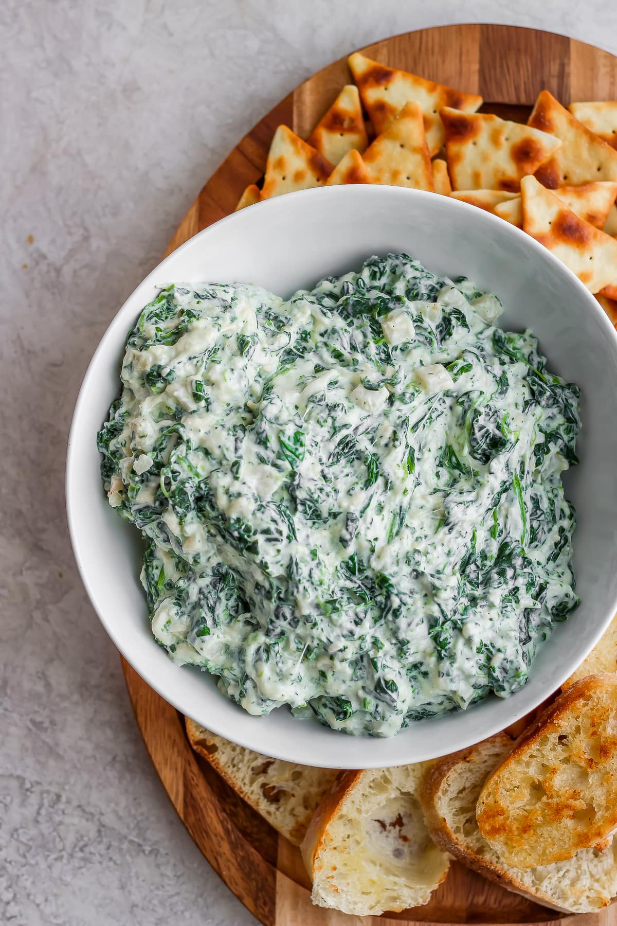 a bowl of crockpot spinach dip on a plate of pita chips