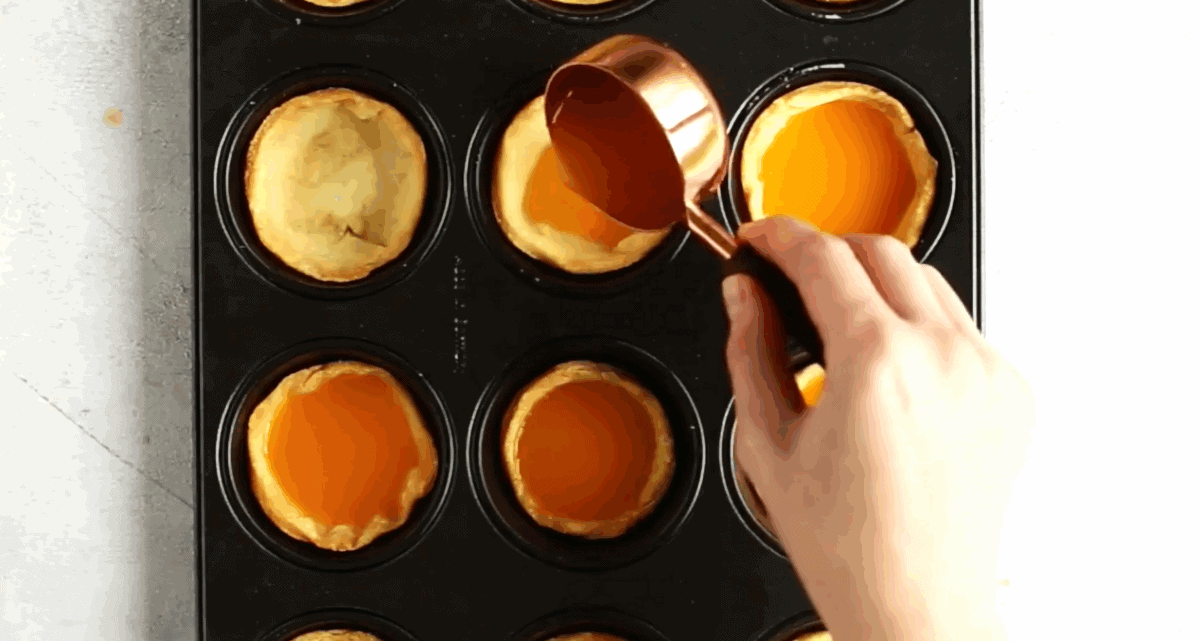 Pouring the pumpkin filling into the crust linked muffin tin. 